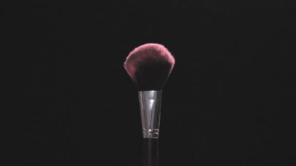 Cepillos de maquillaje con polvo rosa sobre fondo negro en cámara lenta — Vídeos de Stock