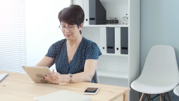 Medelålders kvinna i office arbetar på digitala tablett — Stockvideo