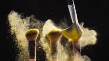 Siyah zemin üzerine altın kozmetik tozu ile kozmetik fırçalar