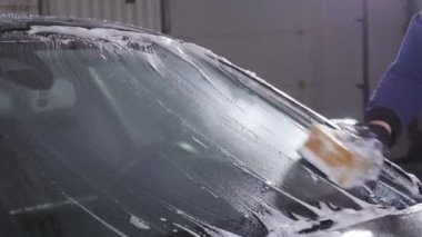 Bir adam araba cam yıkar. El ile araba yıkama kavramı