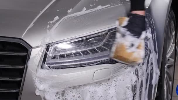 Чоловік миє фари автомобіля. Концепція ручної мийки автомобіля — стокове відео