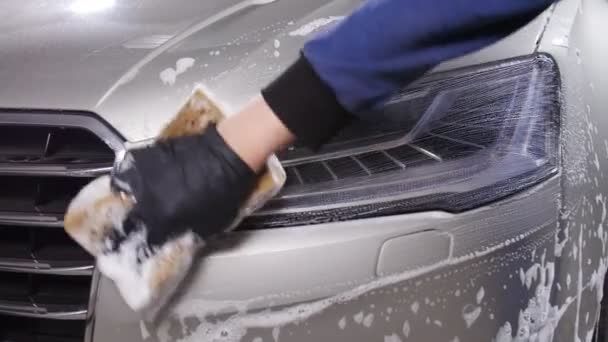 Un hombre lava los faros del coche. Concepto de lavado manual de automóviles — Vídeos de Stock