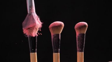 Makyaj ve güzellik konsepti. Siyah arkaplanda pembe toz patlaması olan fırça