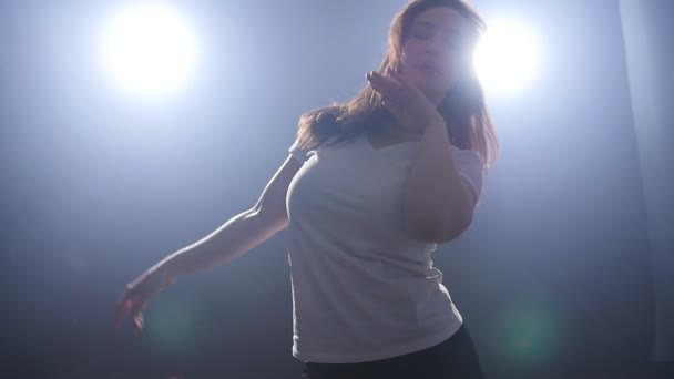 Έννοια του χορού. Νεαρή γυναίκα που χορεύει, με φως στο φόντο — Αρχείο Βίντεο