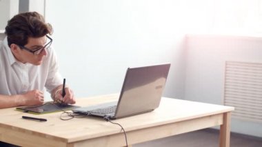 Office iş kavramı. Dizüstü ve tablet ile masa başında oturan genç grafik tasarımcı
