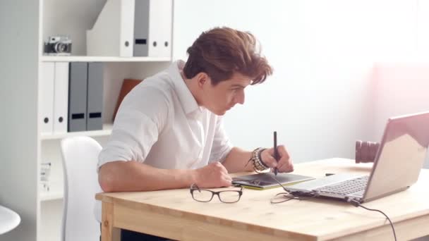 Kantoor werk concept. Grafisch ontwerper zit aan bureau met laptop en tablet — Stockvideo