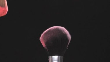 Pembe toz siyah bir arka plan ile iki makyaj fırçaları