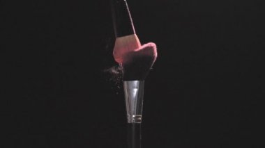 Pembe toz siyah bir arka plan ile iki makyaj fırçaları