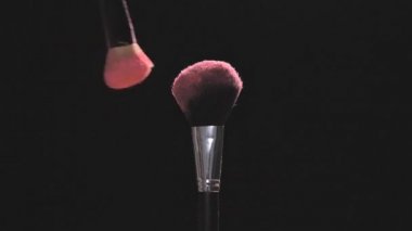 Pembe toz siyah bir arka plan ile iki makyaj fırçaları