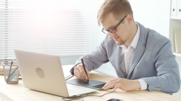 Concepto de trabajo de oficina. Un joven diseñador masculino trabaja en una tableta gráfica — Vídeo de stock