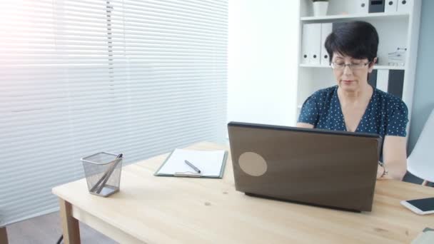 Attraktive reife Geschäftsfrau, die im Büro am Laptop arbeitet — Stockvideo