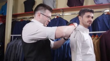 Erkek takım elbise kavramı. Satıcı alıcı bir takım elbise giyim mağazasında seçmek yardımcı olur.