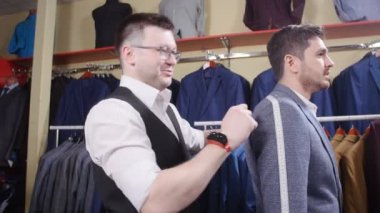 Erkek takım elbise kavramı. Satıcı alıcı bir takım elbise giyim mağazasında seçmek yardımcı olur.