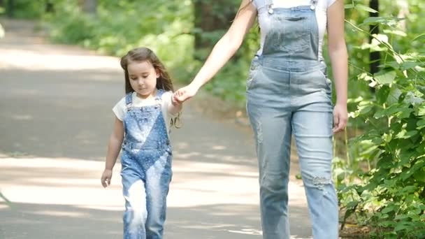 Familienkonzept. junge Mutter und Tochter halten sich an den Händen und gehen — Stockvideo