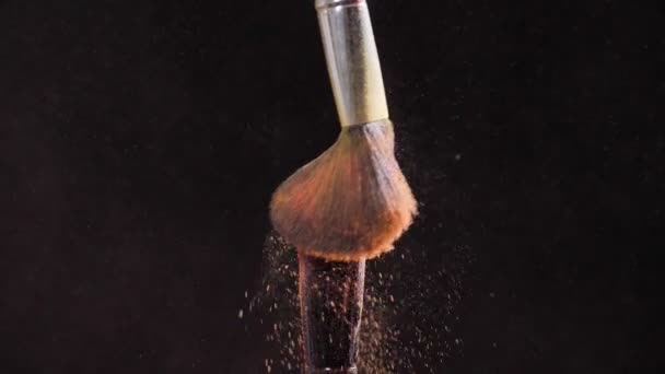 Concept van cosmetica en schoonheid. Make-up penselen met roze poeder explosie op zwarte achtergrond — Stockvideo