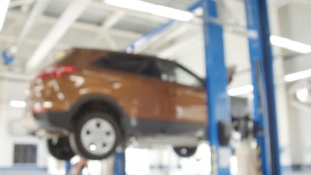 Fondo borroso: Técnico de coches reparando el coche en el garaje — Vídeos de Stock