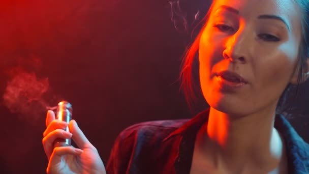 Concepto de vida nocturna. Mujer joven fuma cigarrillo electrónico en luz de color — Vídeos de Stock