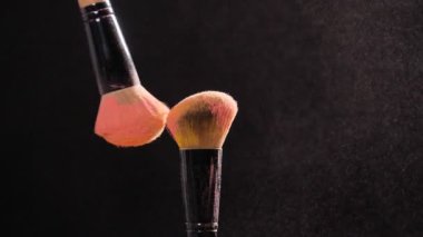 Kozmetik ve güzellik kavramı. Siyah arka plan üzerine pastel pembe kozmetik tozu ile kozmetik fırça