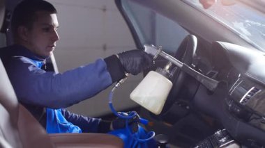 Araba iç temizlik kavramı. Bir adam bir araba kimyasallarla temizler