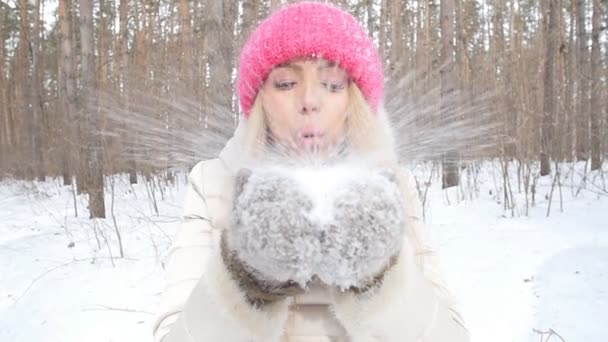 Concept of winter entertainment. Young woman having fun blowing fresh snow from her hands — Stock Video