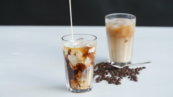 Concept of coffee and cocktails. Cream poured into coffee with ice — Stock Video