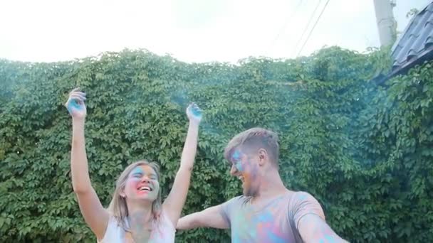 Mladý šťastný pár baví hrát si s barevnými holi prášek — Stock video