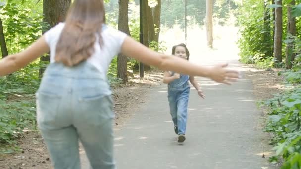 Koncept rodziny. Cute dziewczynka biegnie do objęcia matek w parku — Wideo stockowe