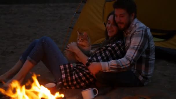 Concept d'amitié, d'amour et de relations. Jeune couple heureux assis avec feu de camp sur la plage la nuit — Video