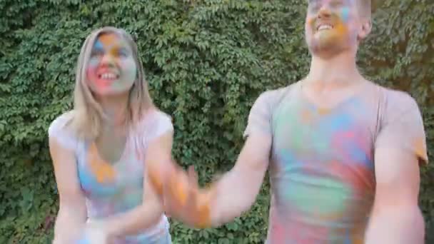 Joyeux jeune couple jouant avec des peintures colorées — Video