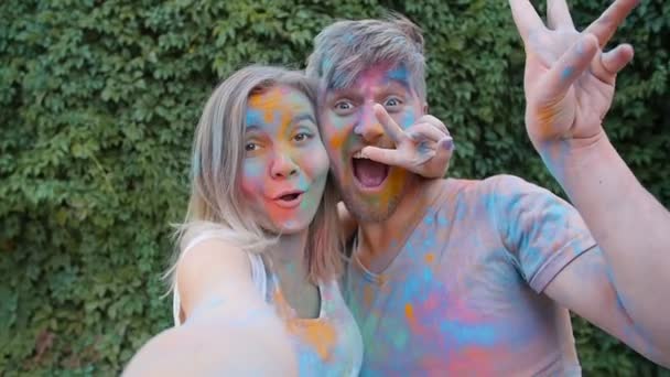 Happy νεαρό ζευγάρι παίζει με πολύχρωμα χρώματα — Αρχείο Βίντεο