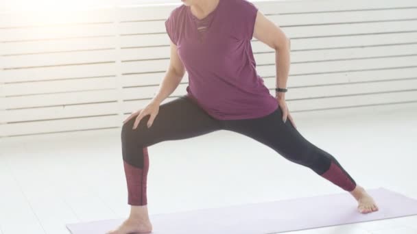 Koncepce harmonie, sport a zdraví. Žena středního věku dělá jógu v bílý interiér — Stock video