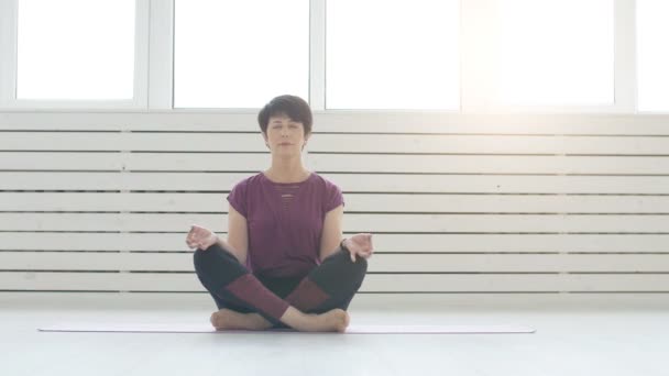 Koncepcja harmonii, sportu i zdrowia. Kobieta w średnim wieku robi joga w białe wnętrza — Wideo stockowe