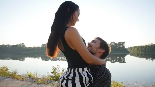 Concepto de amor y relaciones. Pareja joven abrazándose al atardecer junto al río — Vídeos de Stock