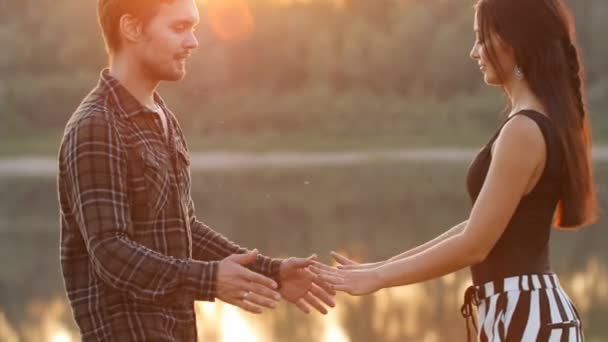 Conceito de amor e relacionamentos. Jovem casal abraçando ao pôr do sol junto ao rio — Vídeo de Stock