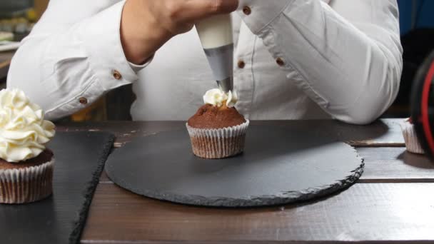 Konzept von Kleinunternehmen und Süßwaren. Bäckerin dekoriert leckeren Cupcake — Stockvideo