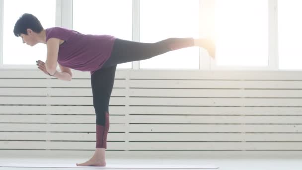 Mujer de mediana edad haciendo yoga en el interior blanco en casa — Vídeo de stock