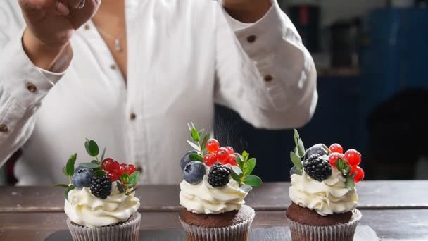 Baker decoreren lekkere cupcake. Poedersuiker bestrooid op taart — Stockvideo