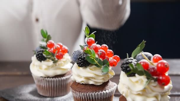 Bäcker schmücken leckere Cupcake. Puderzucker auf Kuchen gestreut — Stockvideo