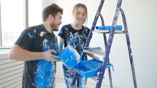 Щаслива чарівна пара розважається і малює кімнату в своєму новому будинку — стокове відео