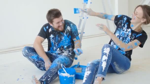 Щаслива чарівна пара розважається і малює кімнату в своєму новому будинку — стокове відео
