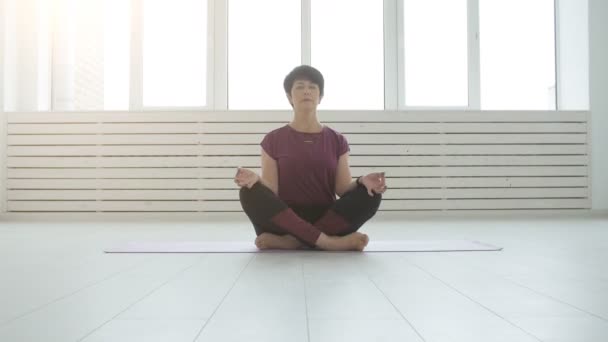 Mujer atractiva yogui de mediana edad practicando yoga en interiores — Vídeos de Stock