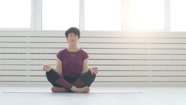 Mellersta åldern yogi attraktiv kvinna utövar yoga inomhus — Stockvideo