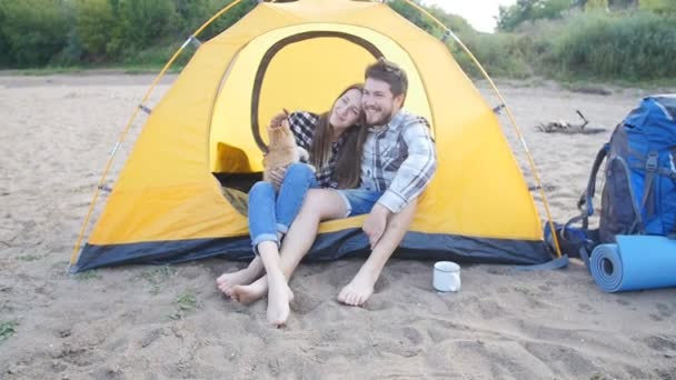 Mladí šťastnému páru s kočkou se sedící v stanu během pěší výlet — Stock video