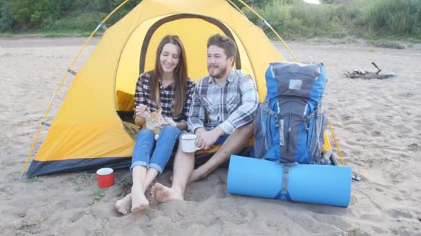 Young gelukkige paar met kat zitten in de tent tijdens het wandelen trip — Stockvideo