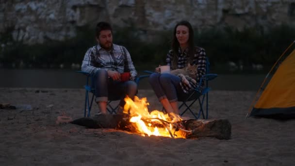 Reizen en liefde concept. Mooie jonge paar in de buurt van open haard op kamp — Stockvideo