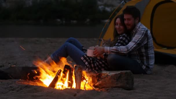 Concepto de viaje y amor. Joven pareja encantadora cerca de la chimenea en el campamento — Vídeo de stock