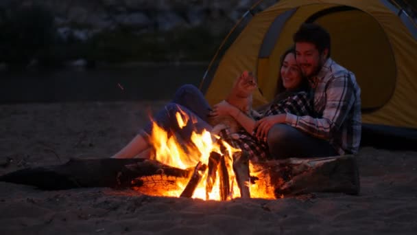 Reizen en liefde concept. Mooie jonge paar in de buurt van open haard op kamp — Stockvideo