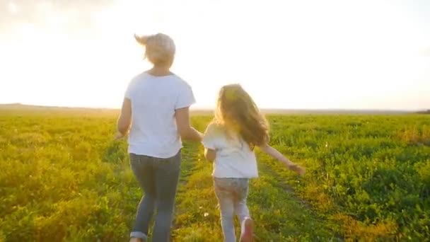 Conceito de família e maternidade. Mãe feliz e criança correm em campo — Vídeo de Stock