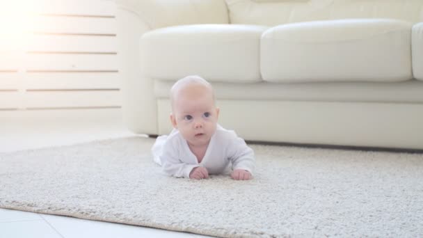 Lindo bebé divertido acostado en una alfombra beige — Vídeos de Stock