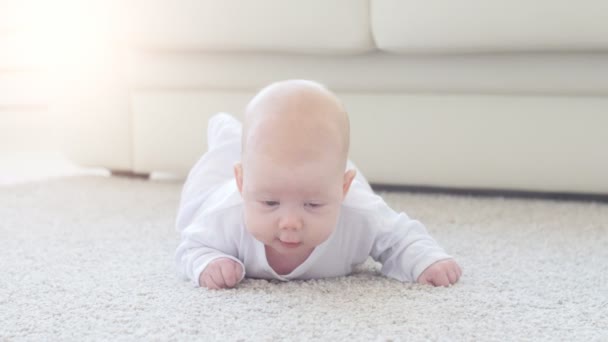 Lindo bebé divertido acostado en una alfombra beige — Vídeos de Stock